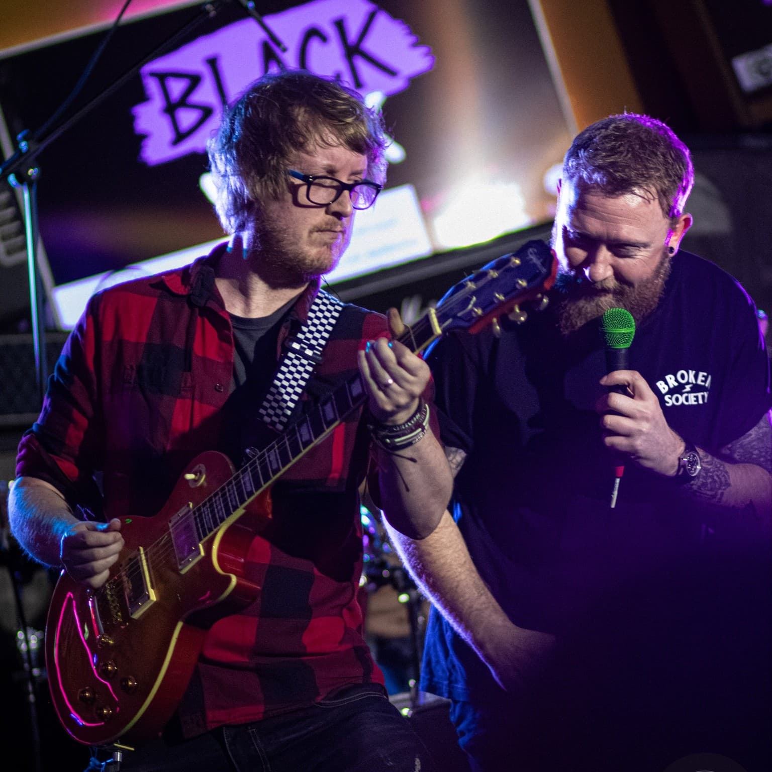 Guitarist and vocalist trading bars under the BLACK sign